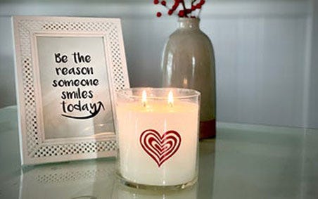 Lit Jar Candle in front of picture that reads Be the reason someone smiles today